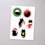 Black Cat Christmas Ornaments Sticker Sheet, sticker sheet on a concrete floor