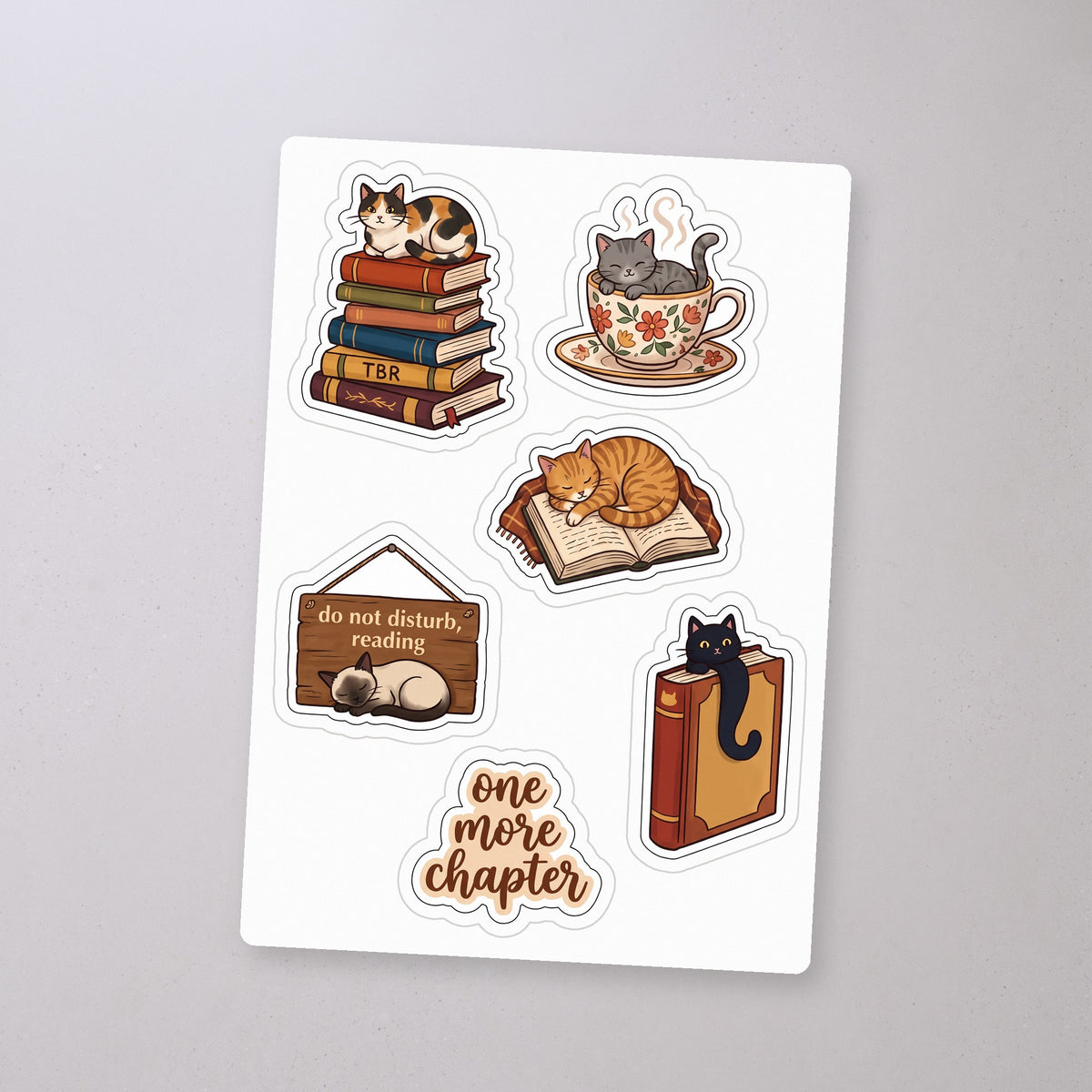 Cozy Cat Reader Sticker Sheet, sticker sheet on a concrete floor