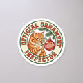 Official Ornament Inspector Cat Sticker on a concrete floor