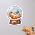 Personalized Snow Globe Cat Sticker with a cat on a concrete floor (sample cat Mango)